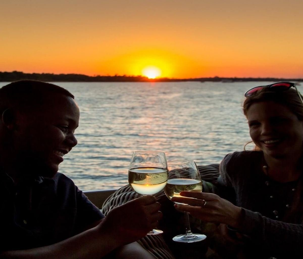 Tourists enjoying wine on a Zambezi sunset cruise